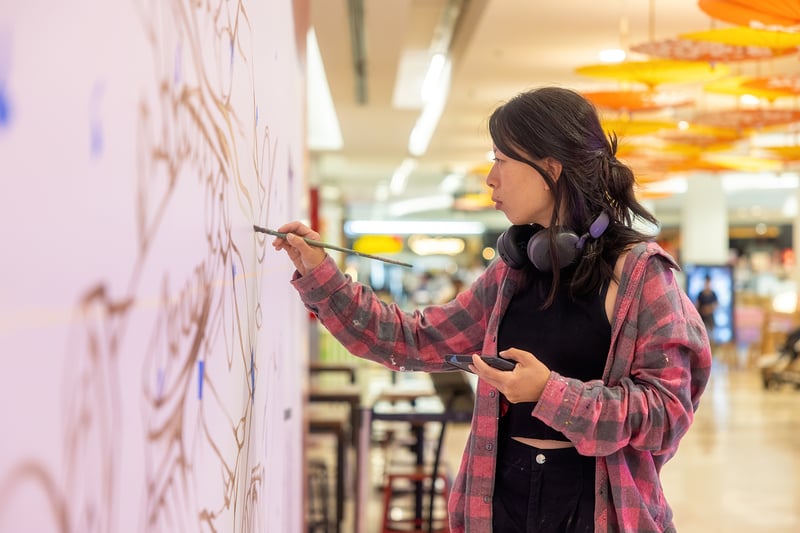 Christina Huynh painting on a wall