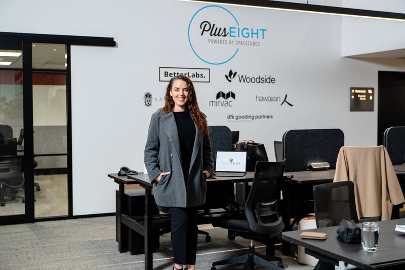 Eliza posing in front of Plus Eight demo wall